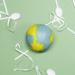 Illustration of Earth's environment impacted by plastic waste on a green background.