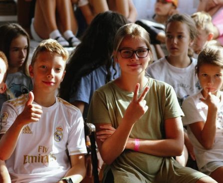 Cheerful group of children sitting together at an indoor event, showcasing friendships and diversity.